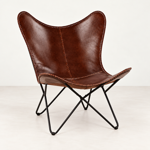 Fauteuil papillon cuir brun — vue de trois quarts sur fond blanc cassé