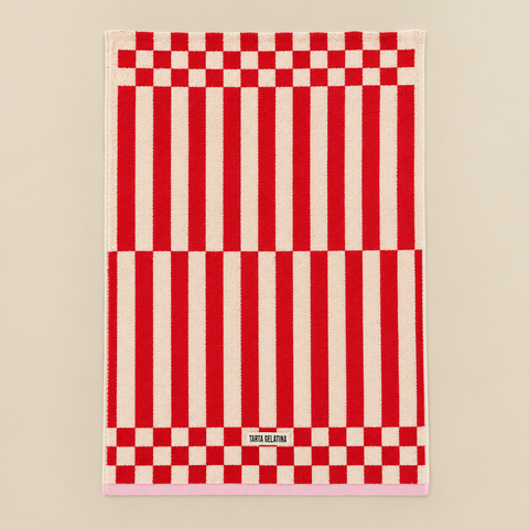 Serviette Clubhouse rouge dépliée sur fond beige