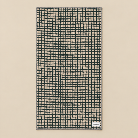 Serviette de bain quadrillée vert forêt dépliée sur fond beige