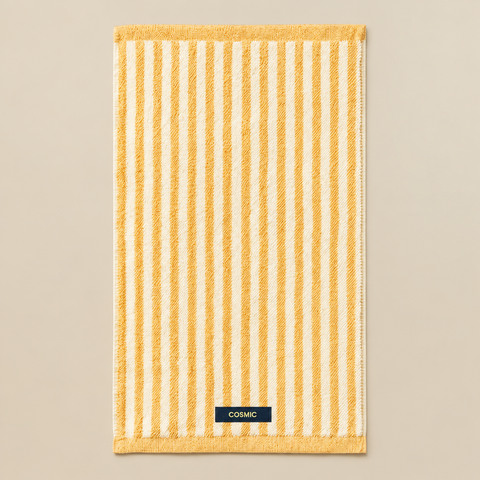 Serviette invité Cosmic jaune miel dépliée sur fond beige