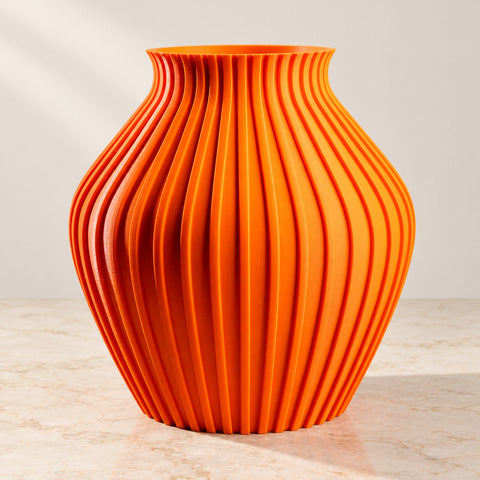 Vase Solaris Wave orange sur un plateau en marbre beige